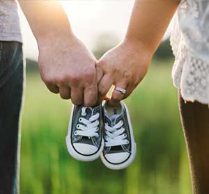 young couple holding hands and a pair of infant tennis shoes